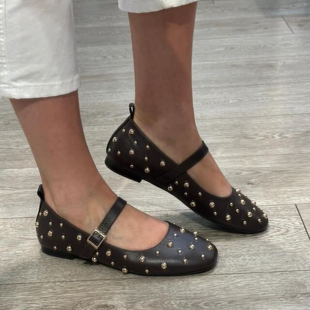 Pedro Anton Brown studded flats worn on a wooden floor