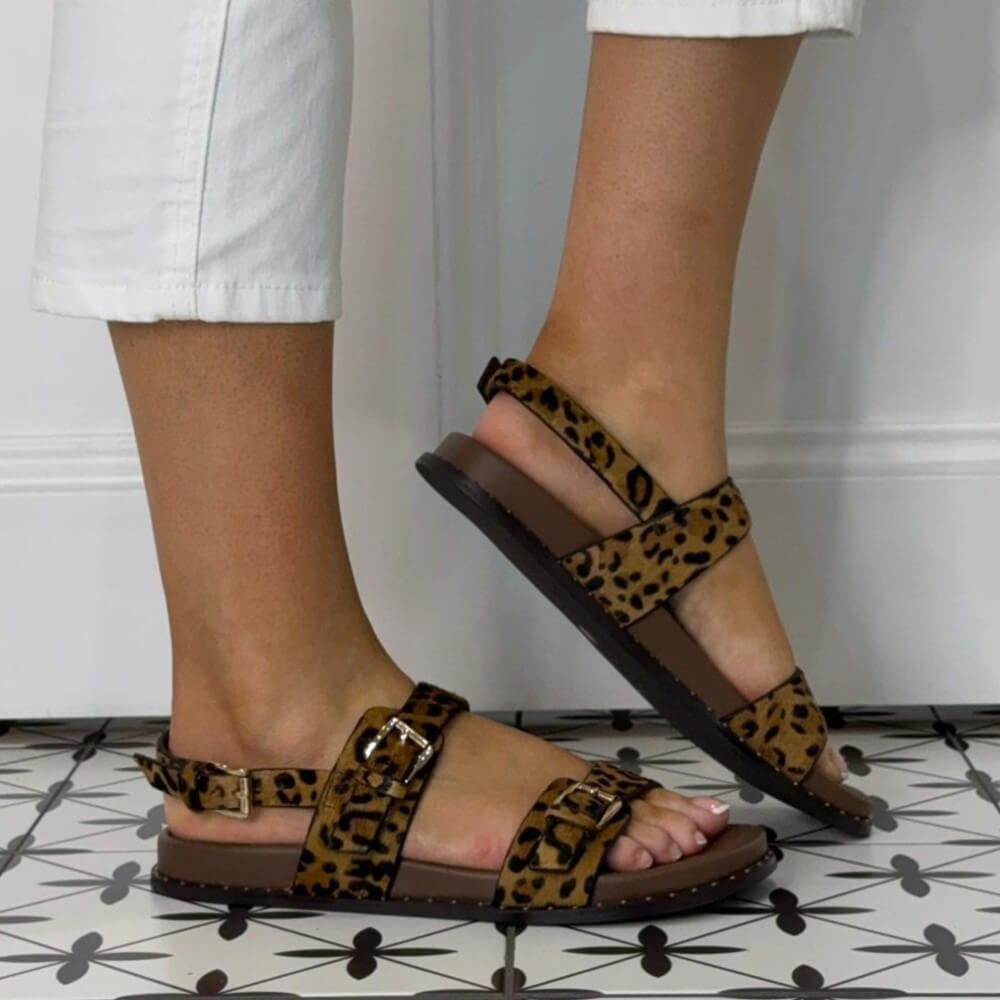 Pedro Anton Leopard print sandals worn with white pants on a patterned floor.