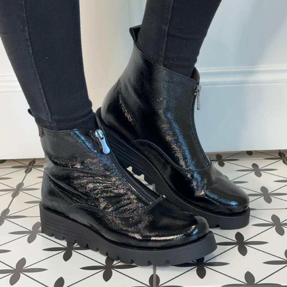 Black patent boots worn with black pants on a patterned floor. Pepe Saenz Wedge Patent Leather Ankle Boots 21544 Black