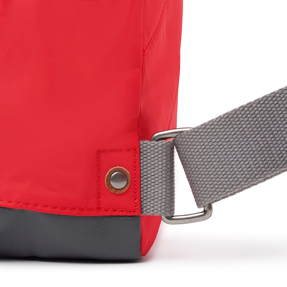 Close-up of a red bag with a gray strap and buckle on a white background