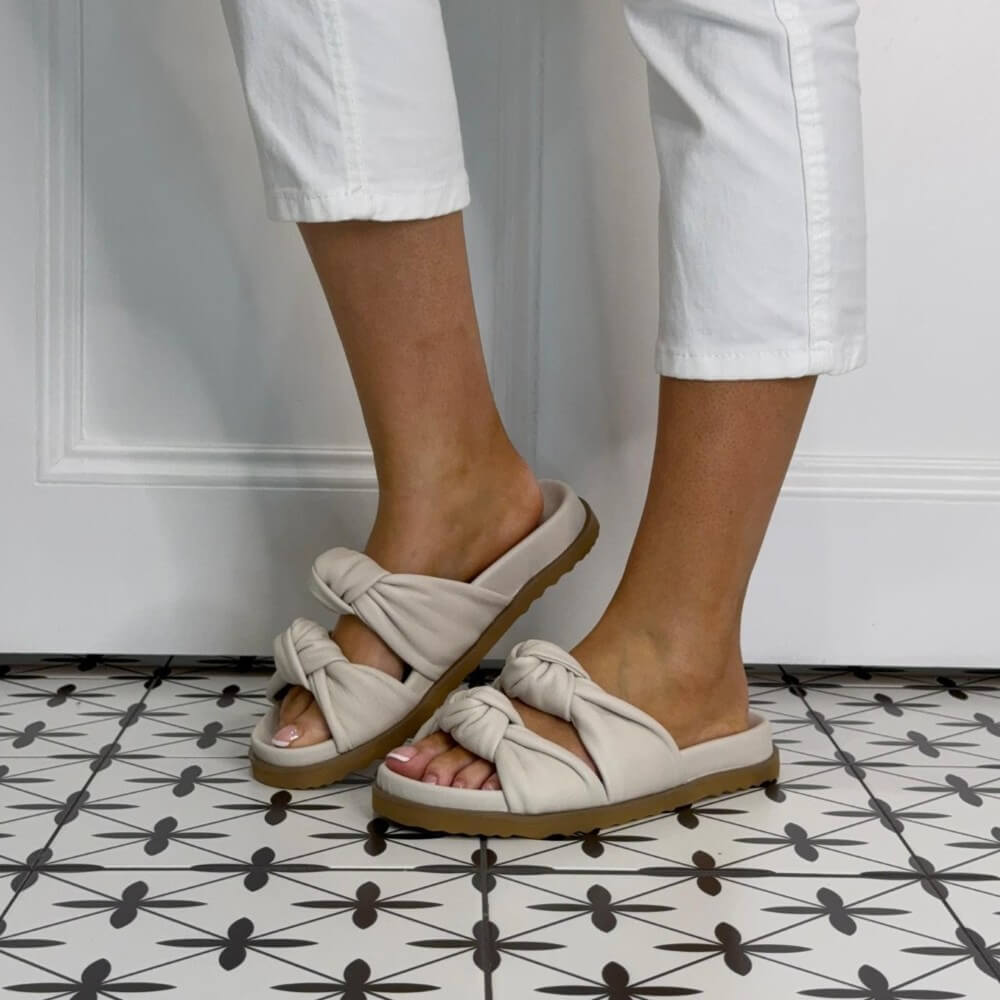 Repo Ivory Leather sandals with knot details worn by a person on a patterned floor.