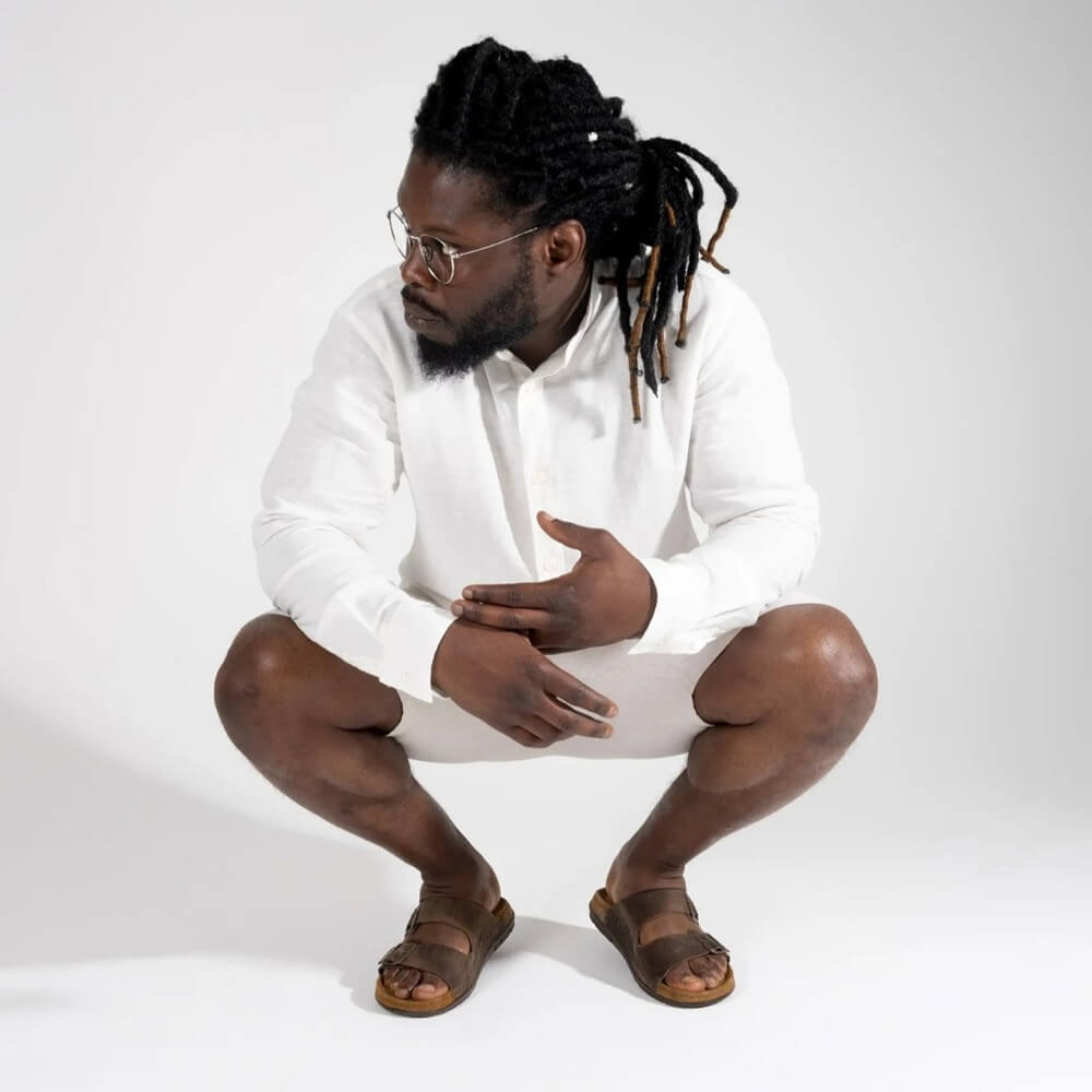 Person wearing white top and shorts with Rohde Brown sandal with double buckle design on a white background