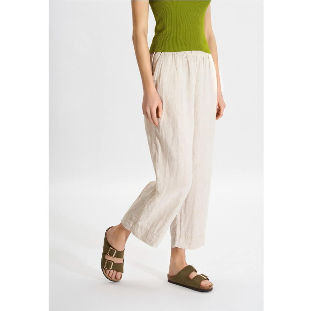 Person wearing Rohde Green sandals with a green top and white pants on a white background