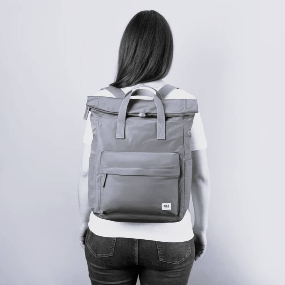 Person wearing a gray backpack on a plain background