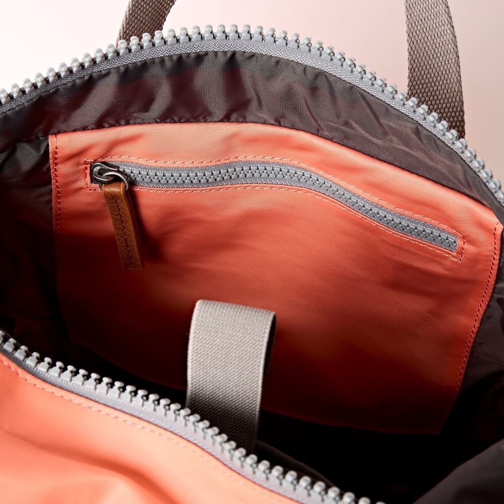 Close-up of a Roka backpack with orange and grey colors.