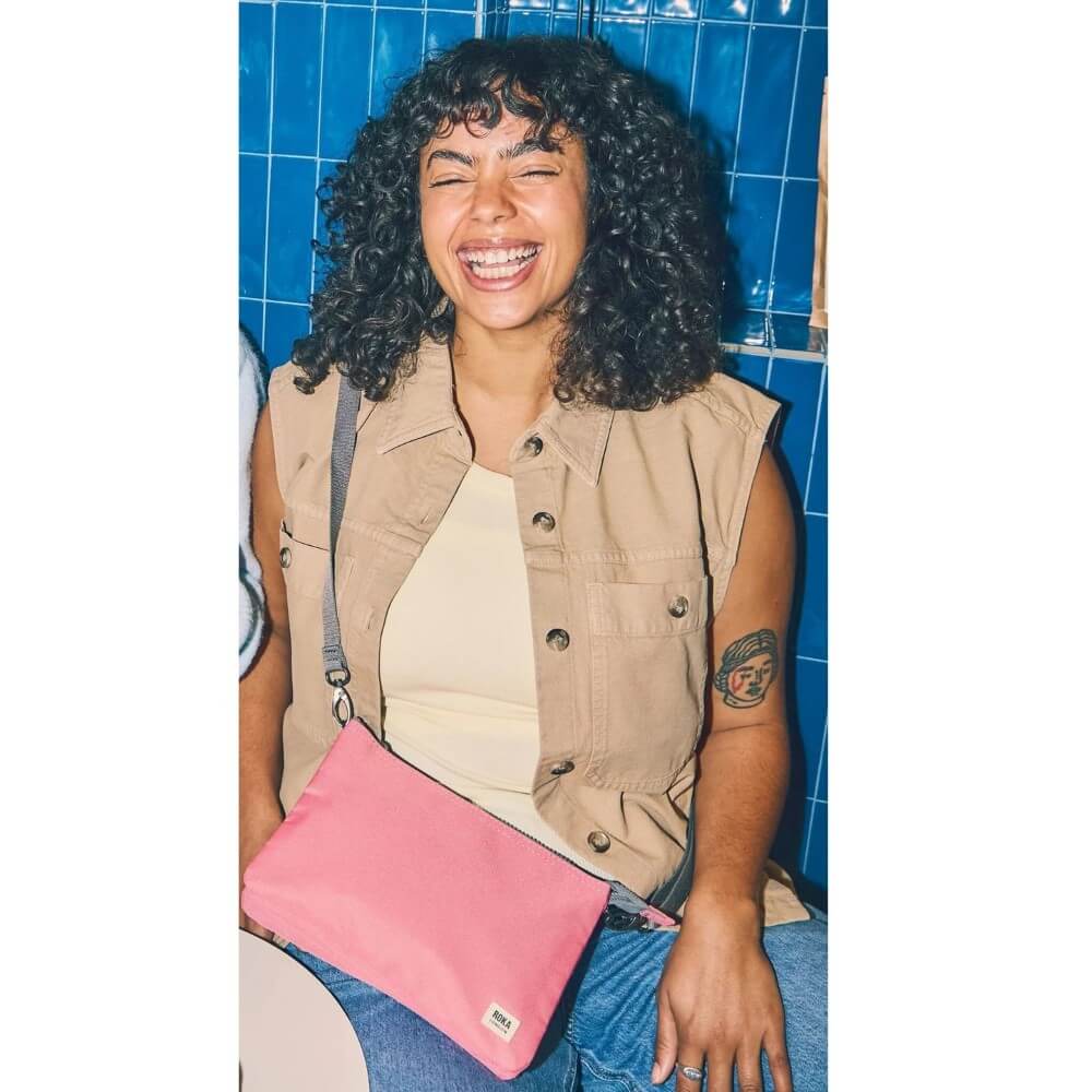 Person holding a pink Roka bag against a blue tiled wall