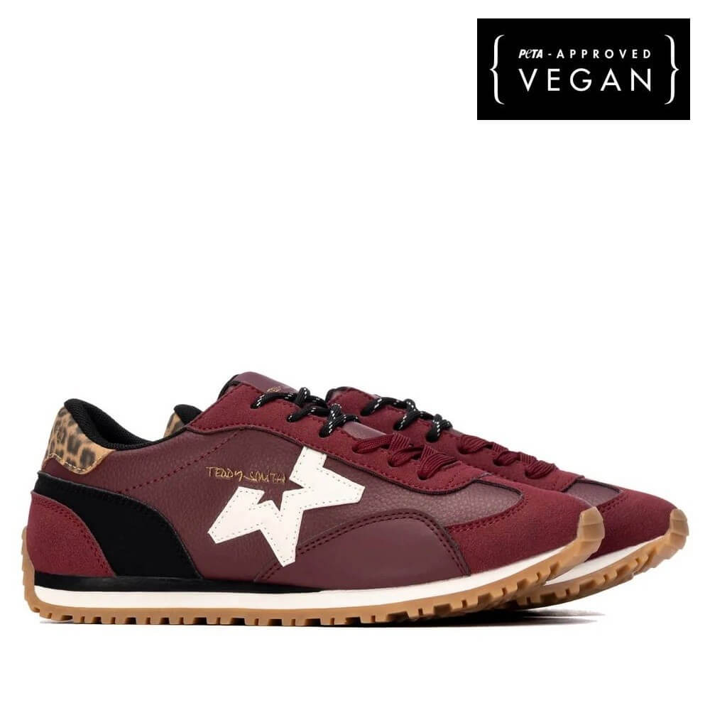 A pair of Teddy Smith low-top sneakers in burgundy and black with a prominent white star logo on the side, a leopard print heel tab, and a gum sole. A black square badge in the top right corner reads 'PTA APPROVED VEGAN'.