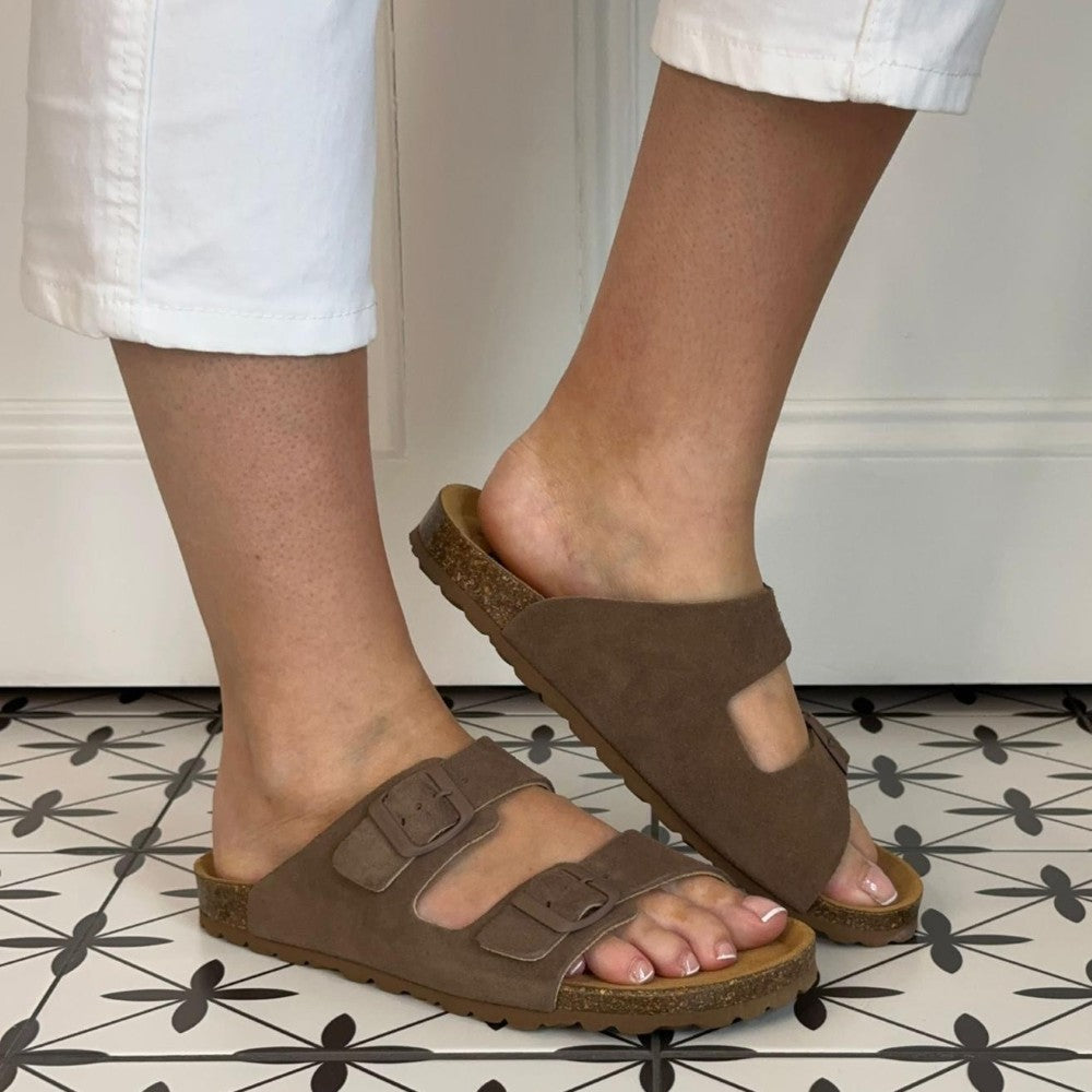 Toni Pons Brown sandals worn with white pants on a patterned floor.