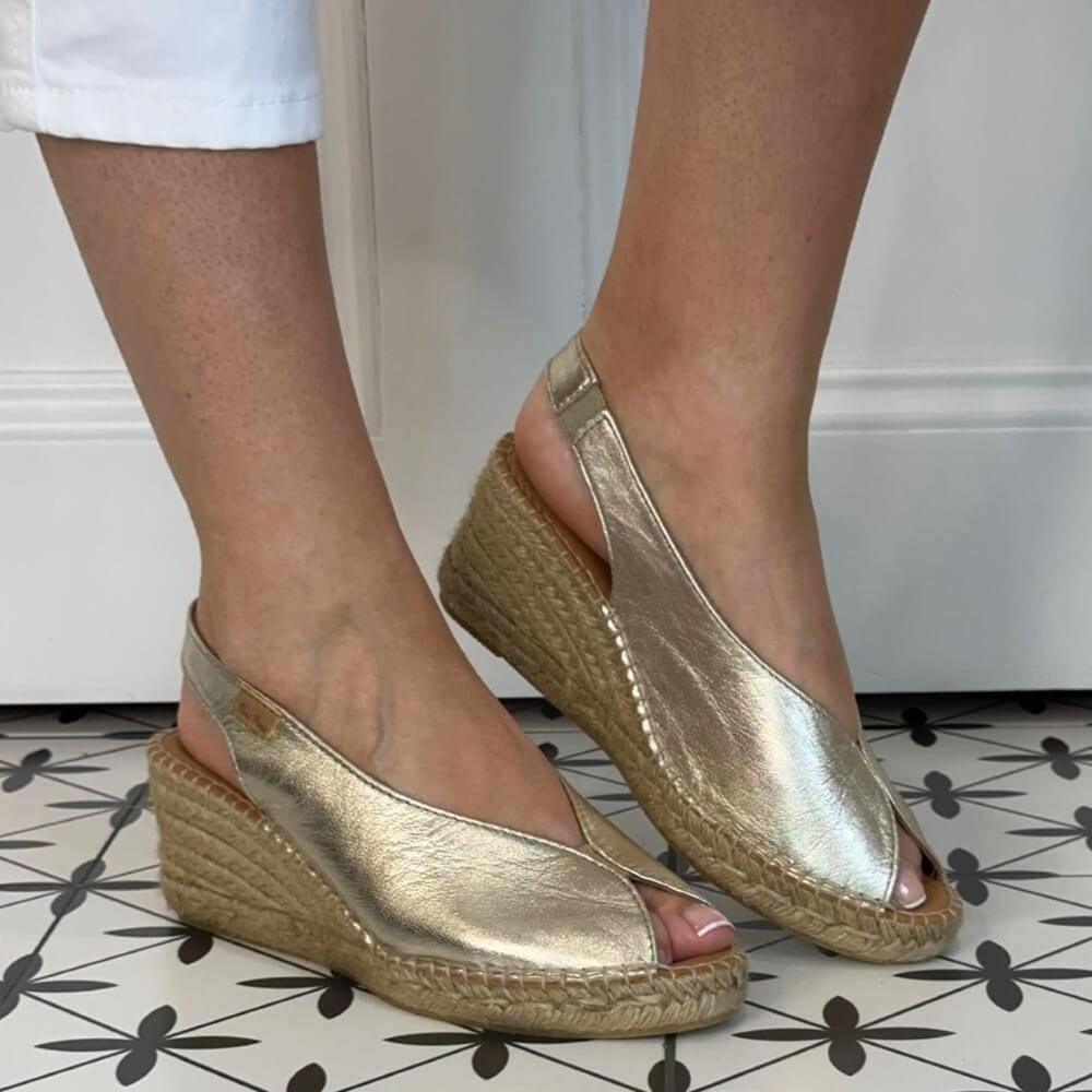 Toni Pons Gold wedge sandals worn indoors on a patterned floor.