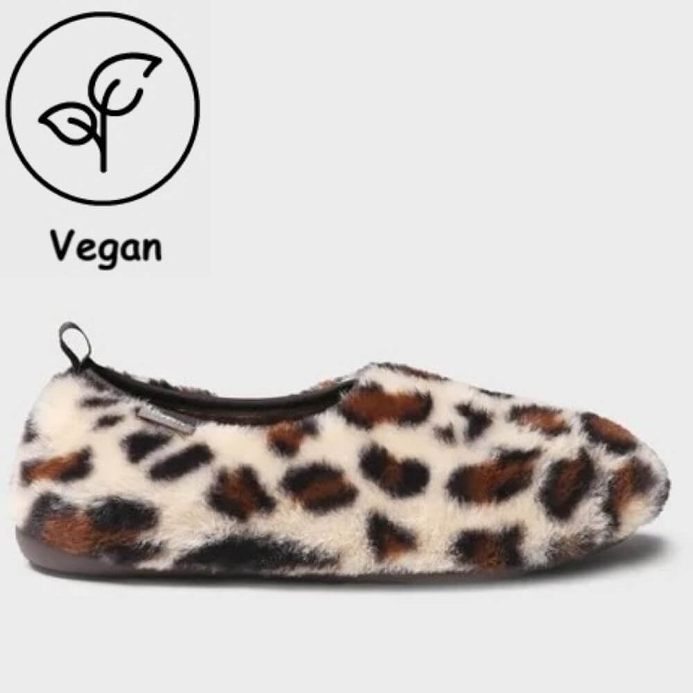 A Toni Pons plush slip-on slipper in a brown, black, and cream leopard print, shown from a side profile on a light grey background. A 'Vegan' leaf icon is displayed in the upper left corner.