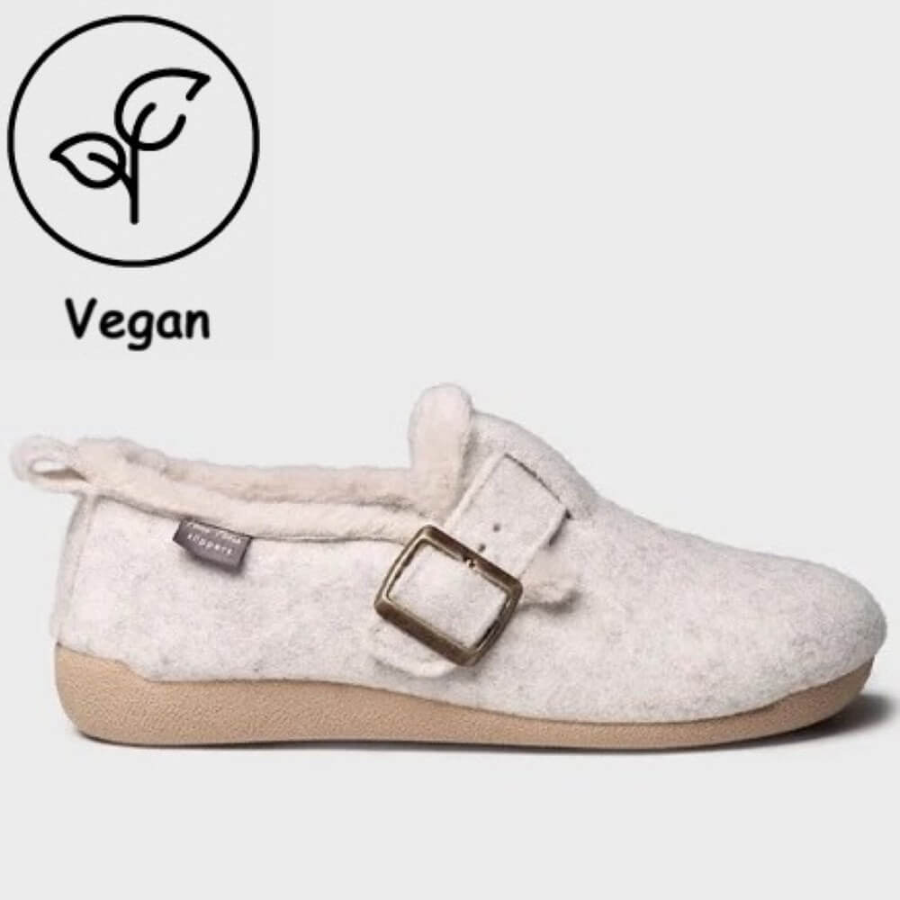 A Toni Pons slip-on felt slipper in a light cream/off-white colour with a beige sole, featuring a decorative buckle strap and a soft fleece lining. A 'Vegan' leaf icon and text are displayed in the top-left corner.