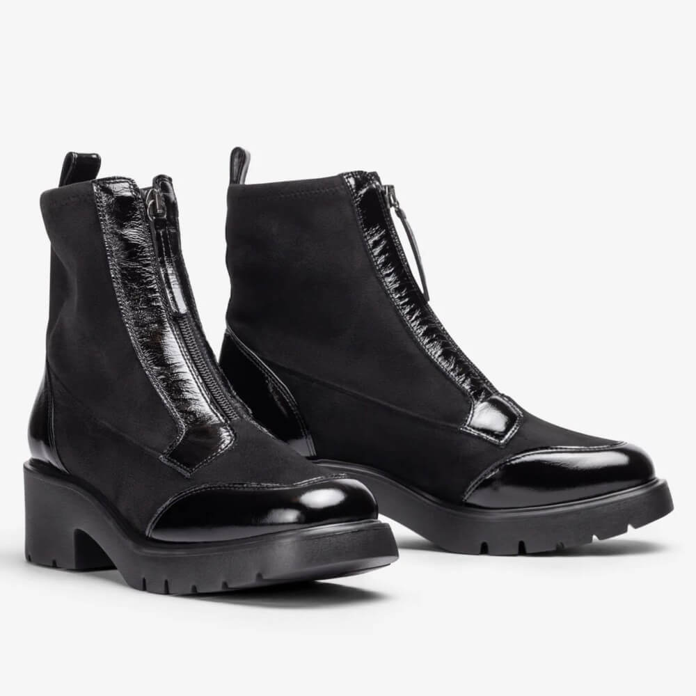 A pair of Unisa black ankle boots with a mix of patent leather and suede materials, featuring side zippers and chunky lug soles, shown against a plain light grey background.