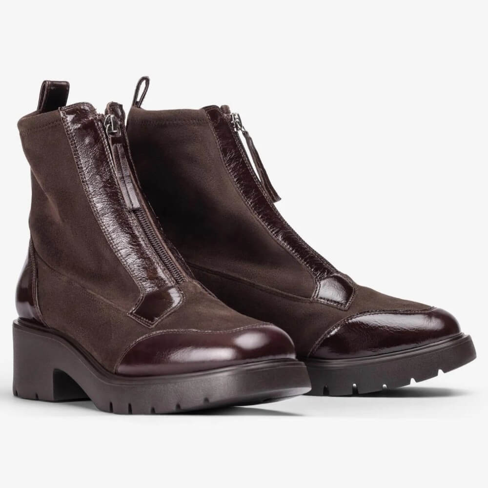A pair of Unisa dark brown ankle boots with a mix of smooth suede and glossy patent leather panels, featuring front zippers and chunky lug soles, shown against a plain white background.