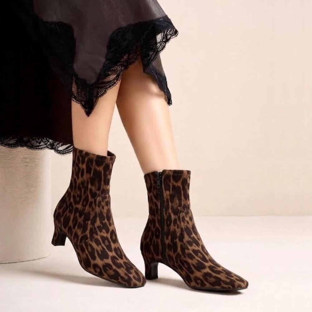 Person Wearing a pair of Unisa Jarret Leopard Print Boots with a black derss
