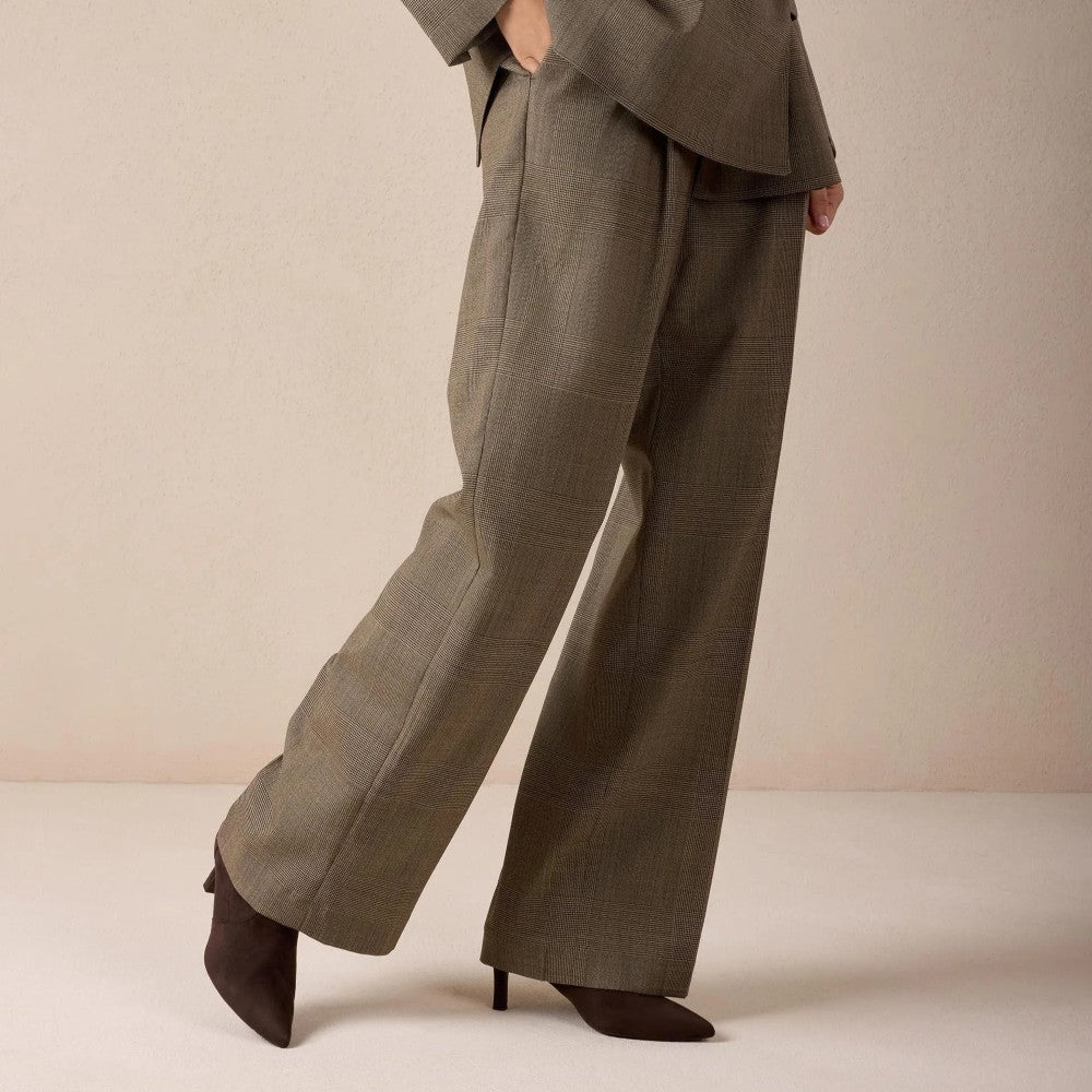 Person wearing a taupe suit and A pair of Unisa dark brown suede ankle boots with pointed toes and kitten heels,