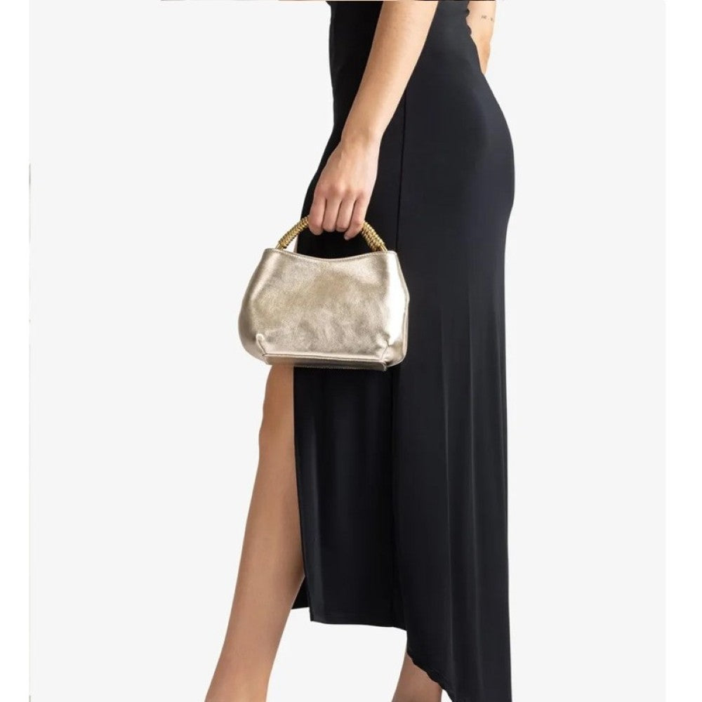 Person holding a Unisa gold metallic handbag with a plain background