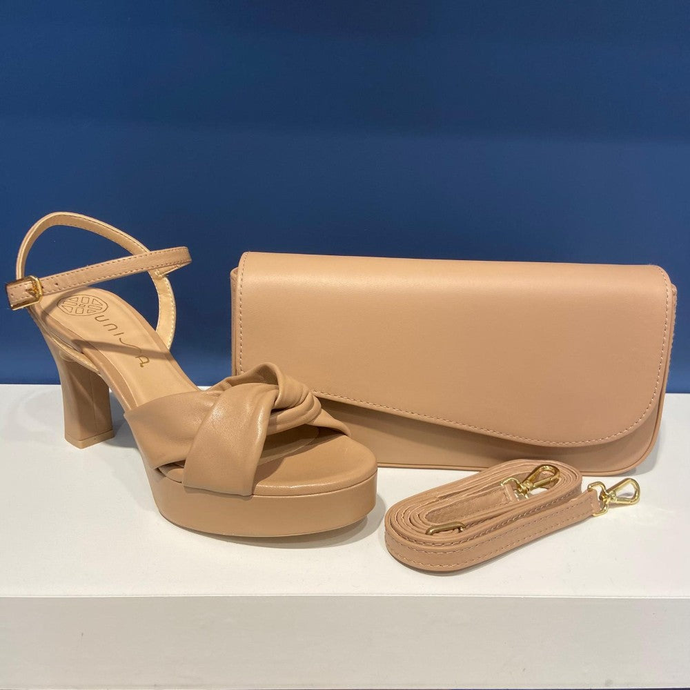 Unisa Beige sandal with a bow and matching handbag on a white surface with a blue background