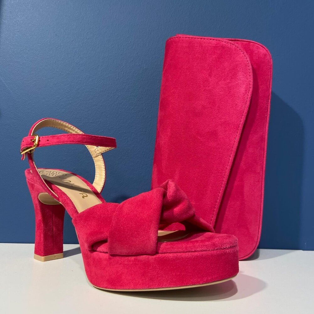 Unisa Pink high-heeled sandal with a matching clutch on a blue background