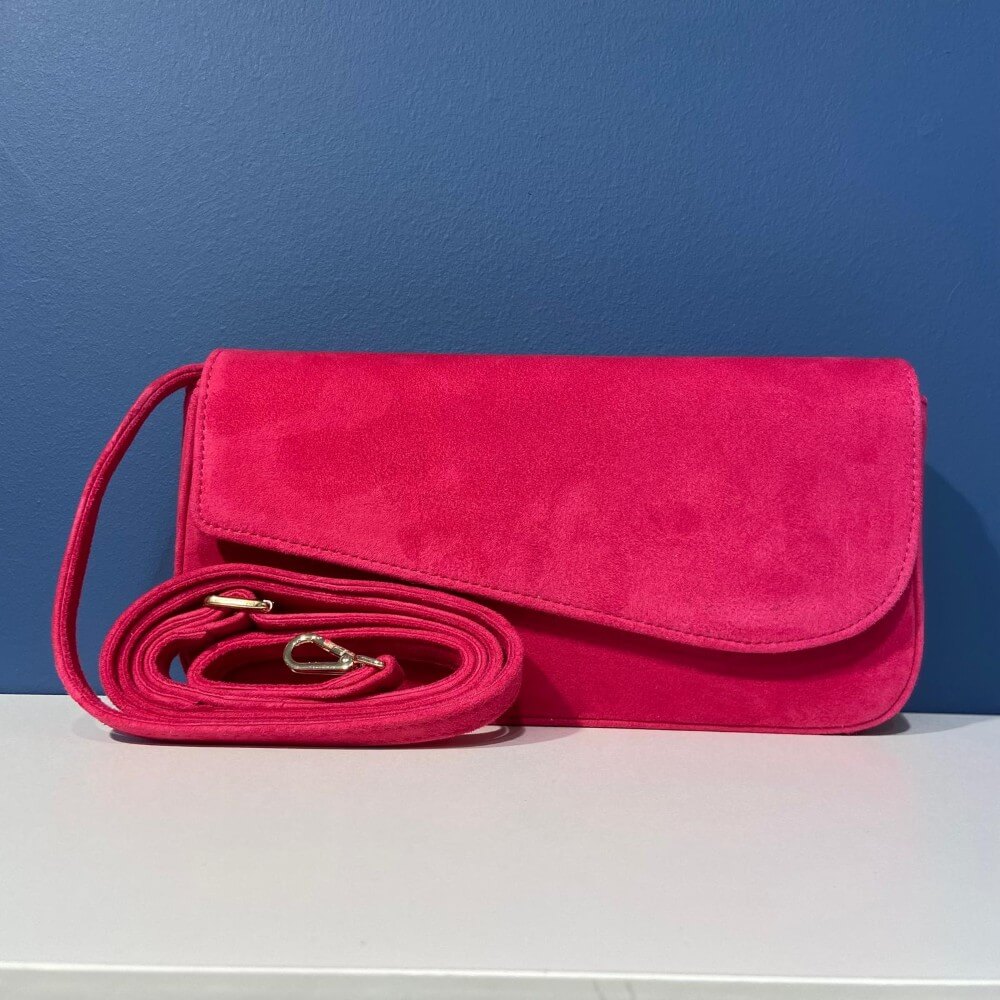Unisa Pink handbag with a strap on a white surface against a blue wall