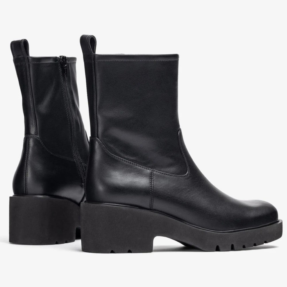 Pair of black leather boots on a light gray background