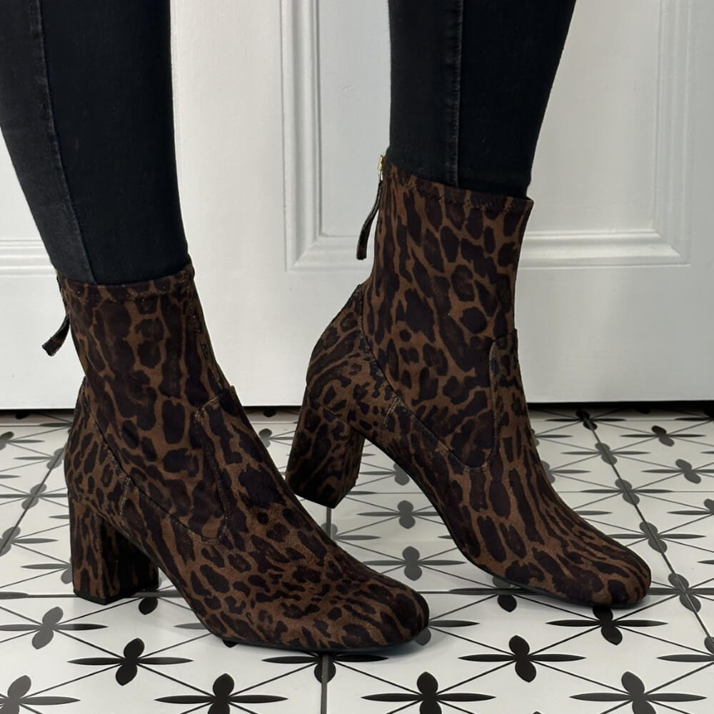 pair of leopard print sock boots with a back zip worn with black jeans an a patterned floor