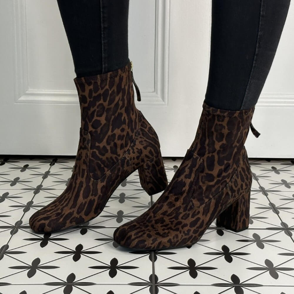 pair of leopard print sock boots with a back zip worn with black jeans an a patterned floor