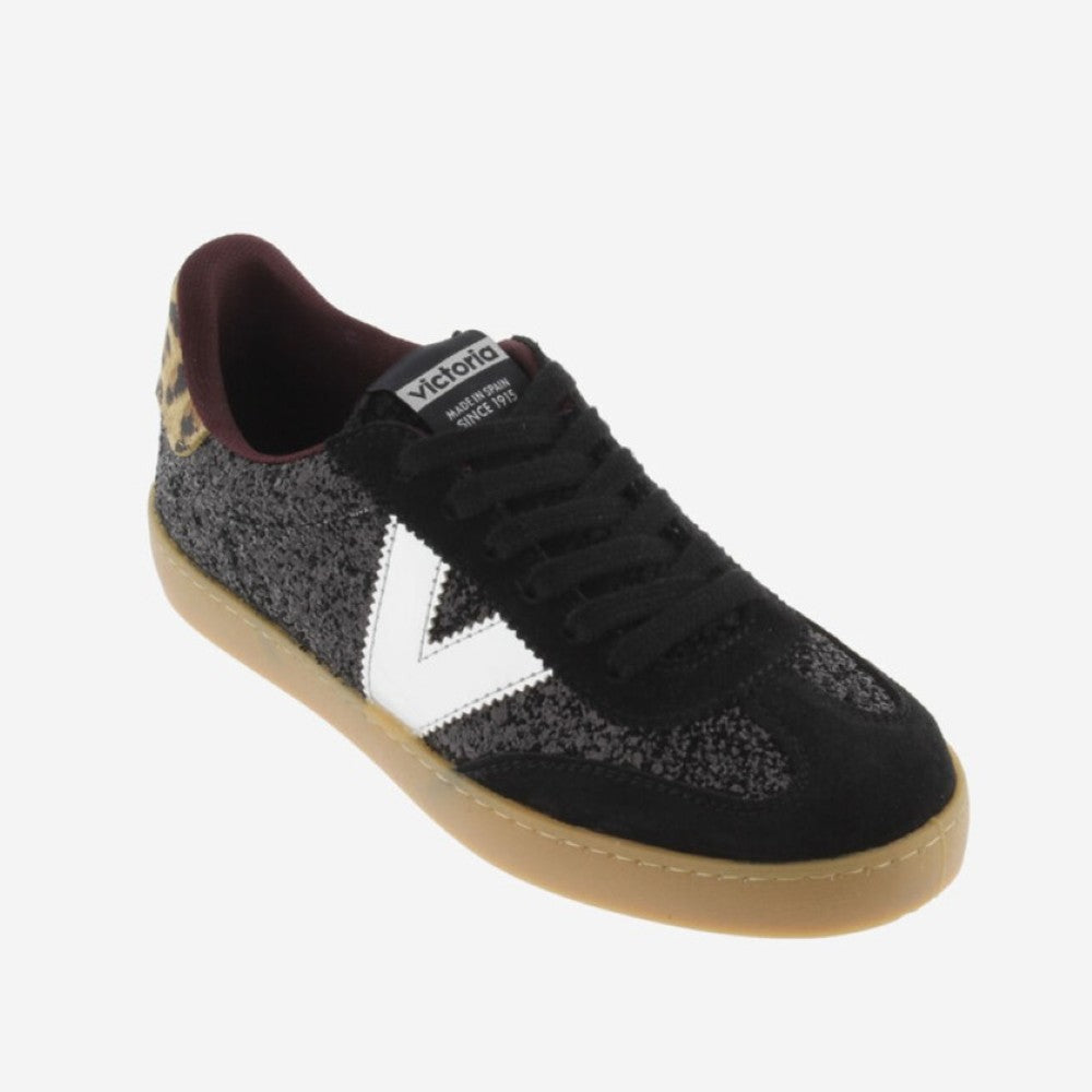 A low-top Victoria sneaker in black suede and textured fabric, featuring a white V logo, black laces, a burgundy interior, and a gum sole, shown on a light gray background.
