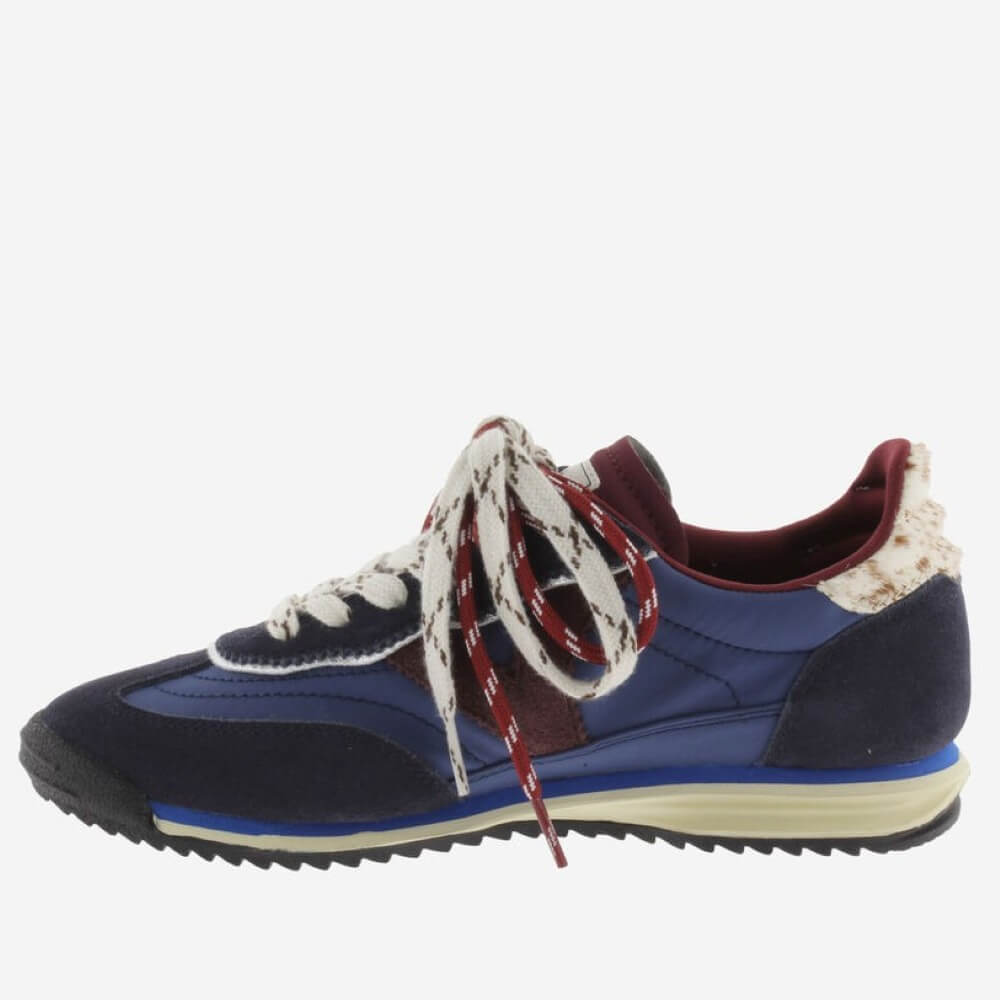 A low-top sneaker in navy blue suede and fabric, featuring burgundy accents, cream laces with red patterned details, and a cream midsole on a light gray background.