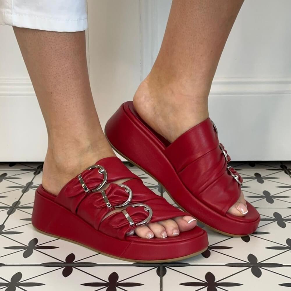 Marco Moreo Red platform sandals with buckles worn on a patterned floor.