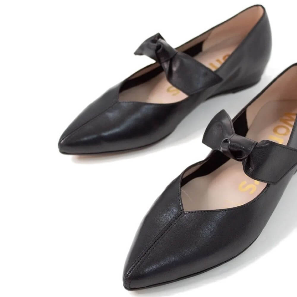 Black pointed-toe shoes with bows on a white background