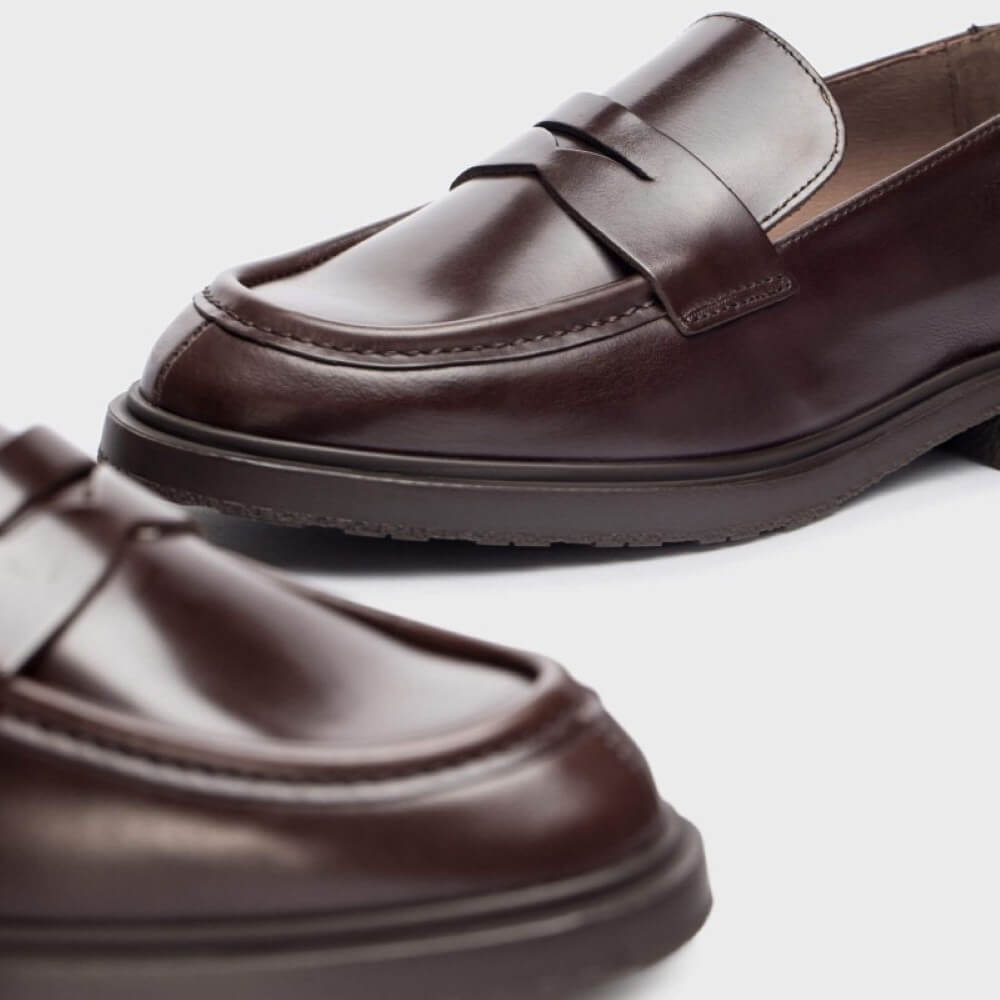 Brown leather loafers on a light gray background
