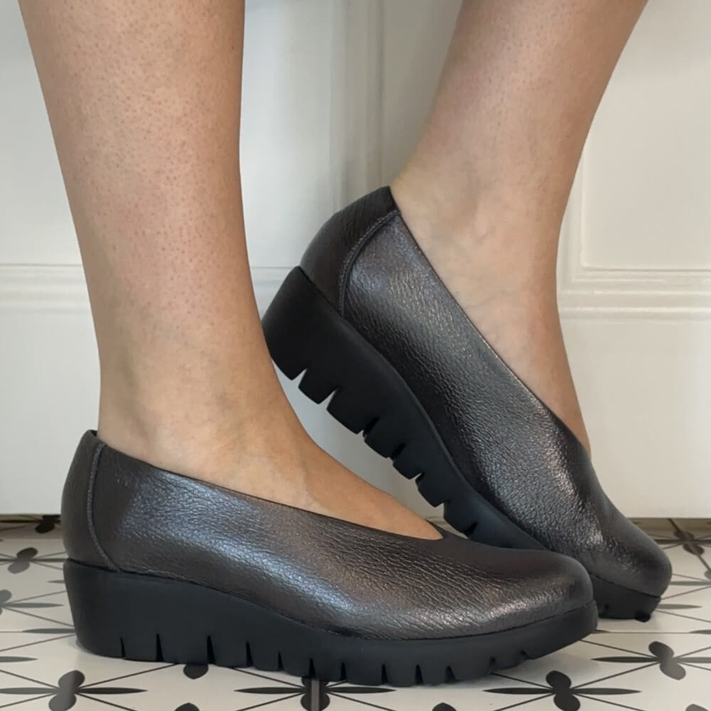 A pair of Wonders women's Plomo leather platform wedge shoes with chunky lug soles, shown on a person's feet against a white panelled wall and patterned tile floor.