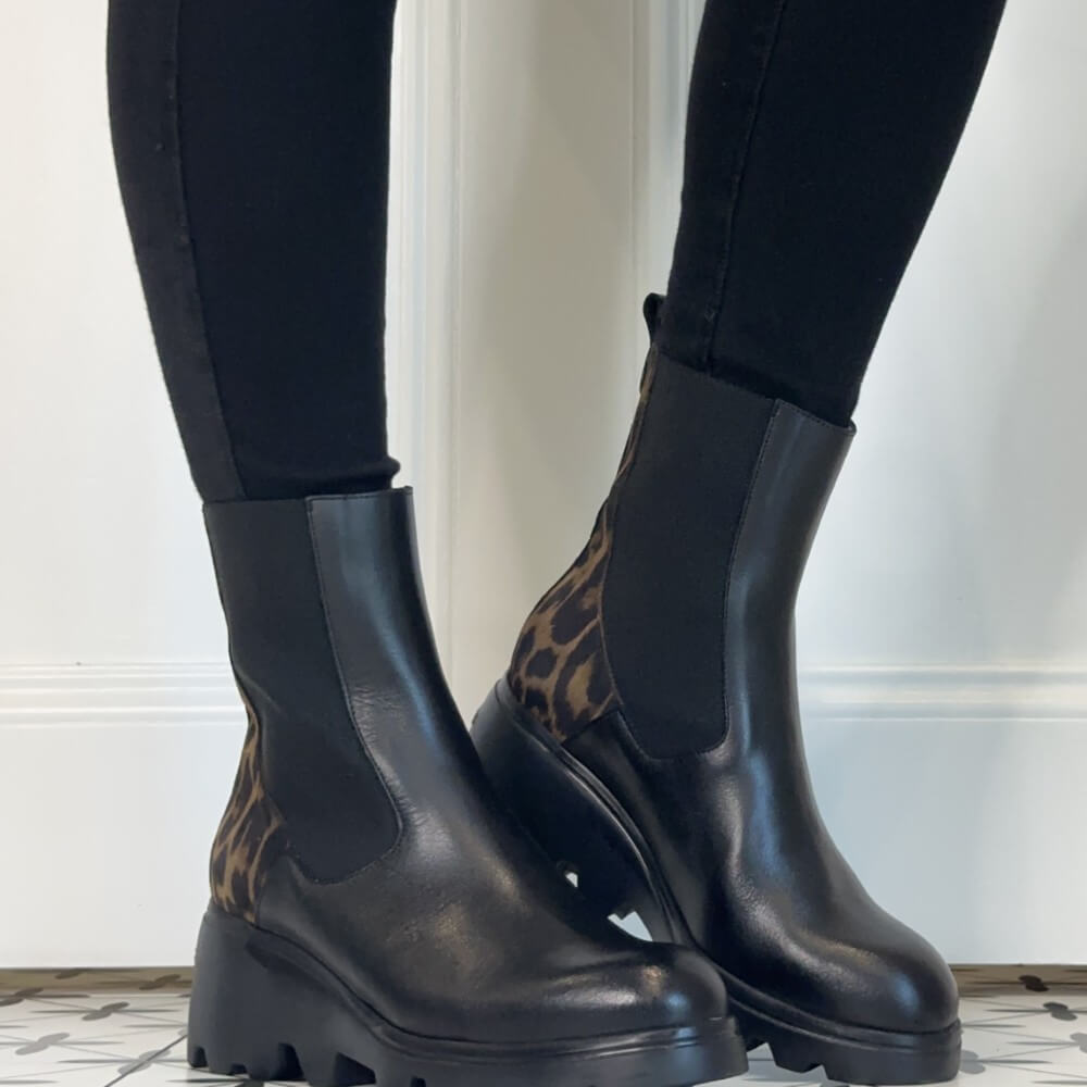 Wonders Black leather Chelsea-style ankle boots with leopard-print fabric panels on the heel and back, worn with black leggings.