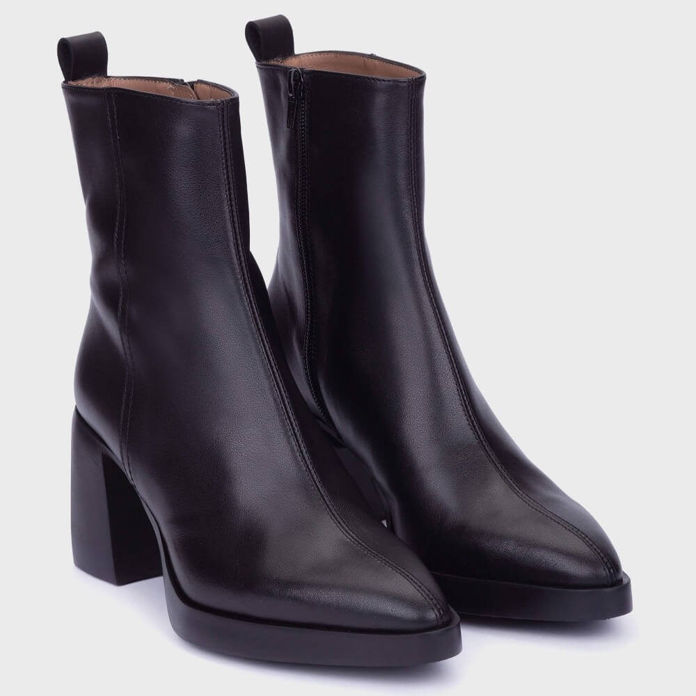 A pair of Wonders black leather ankle boots with a chunky block heel an inside zip and pointed toe, shown on a light grey background.