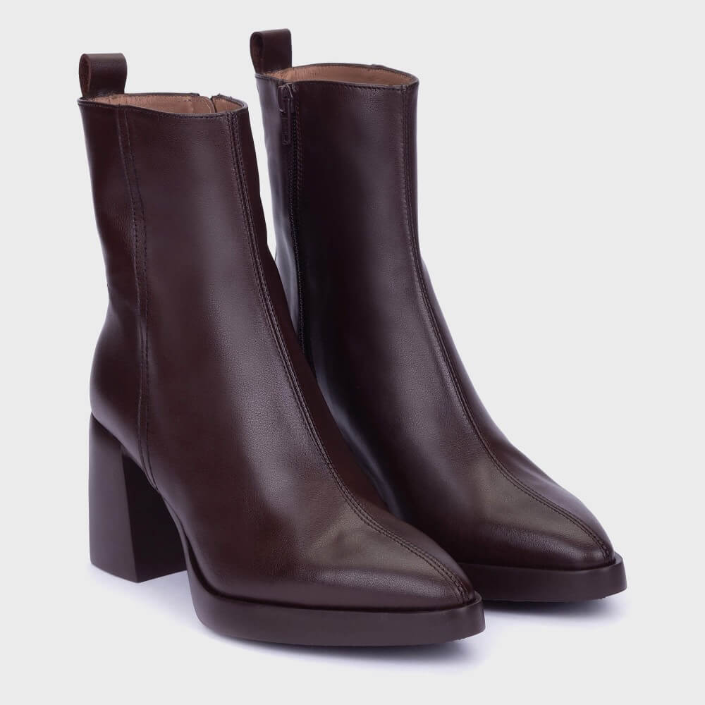 A pair of Wonders dark brown leather ankle boots with block heels, an inside zip and pointed toes, shown on a light grey background.