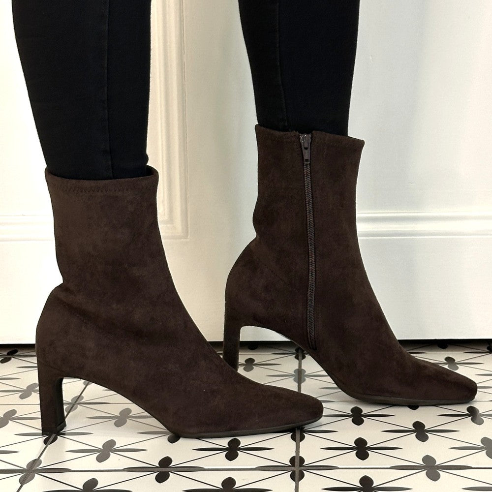 A pair of Wonders dark brown suede ankle boots with kitten heels, worn with black skinny jeans on a black and white patterned tile floor.