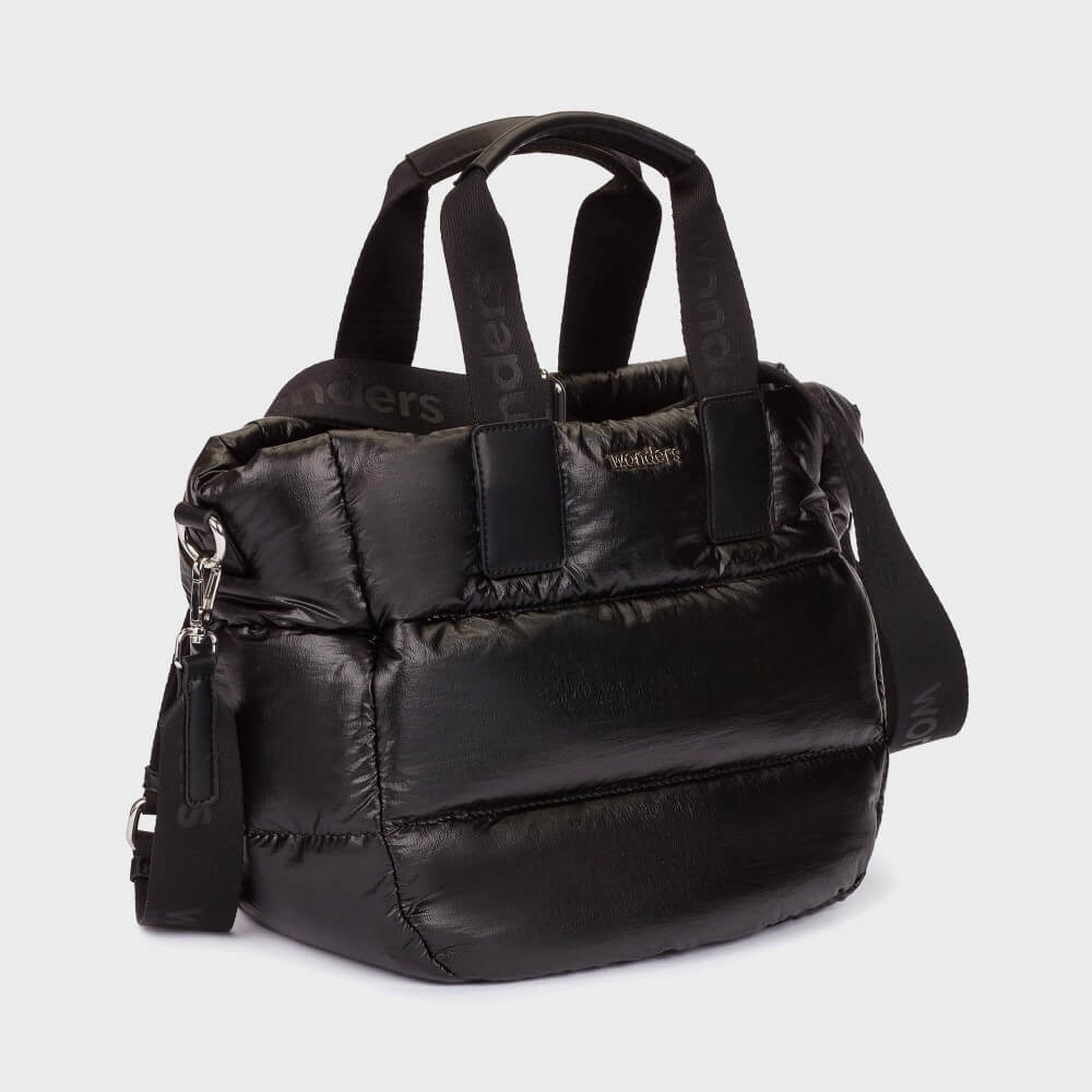 A Wonders black puffer-style tote bag with quilted horizontal stitching, dual top handles, and a detachable shoulder strap, photographed on a light grey studio background.