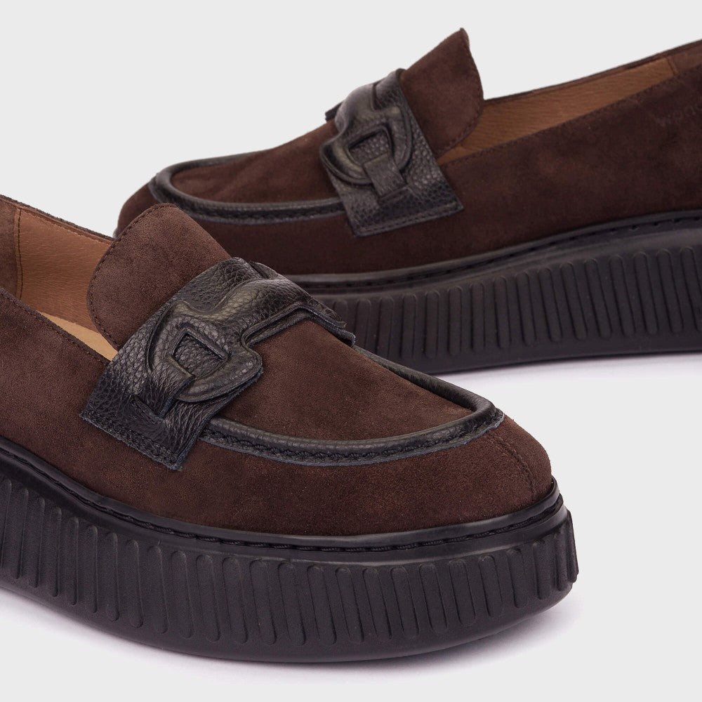 A pair of Wonders dark brown suede platform loafers with black textured buckle straps and thick black platform soles, shown on a light grey background.