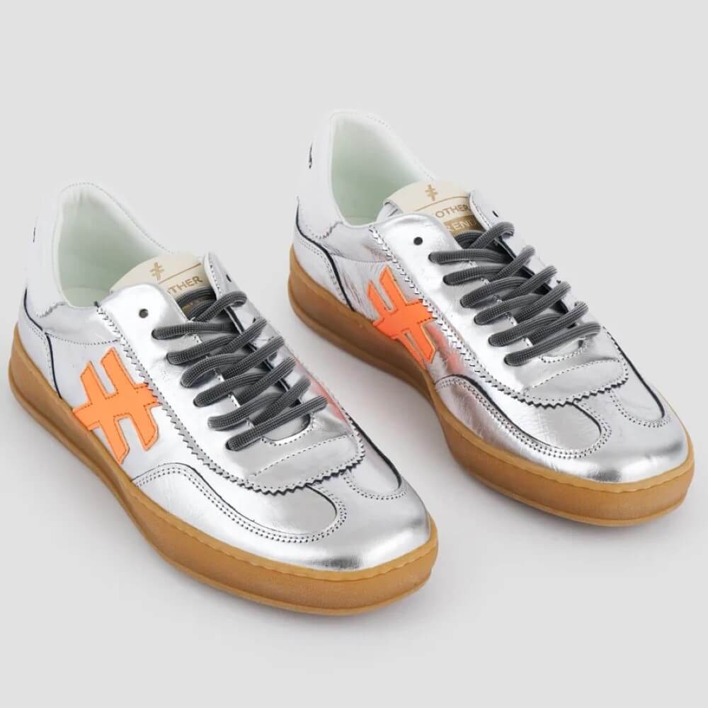 Silver sneakers with orange 'H' logos and brown soles on a light gray background