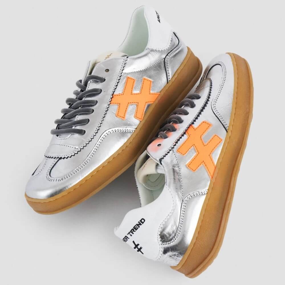 Silver Leather sneakers with orange accents and brown soles on a light grey background