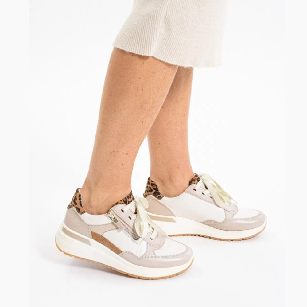 White sneakers with leopard print accents worn by a person on a white background