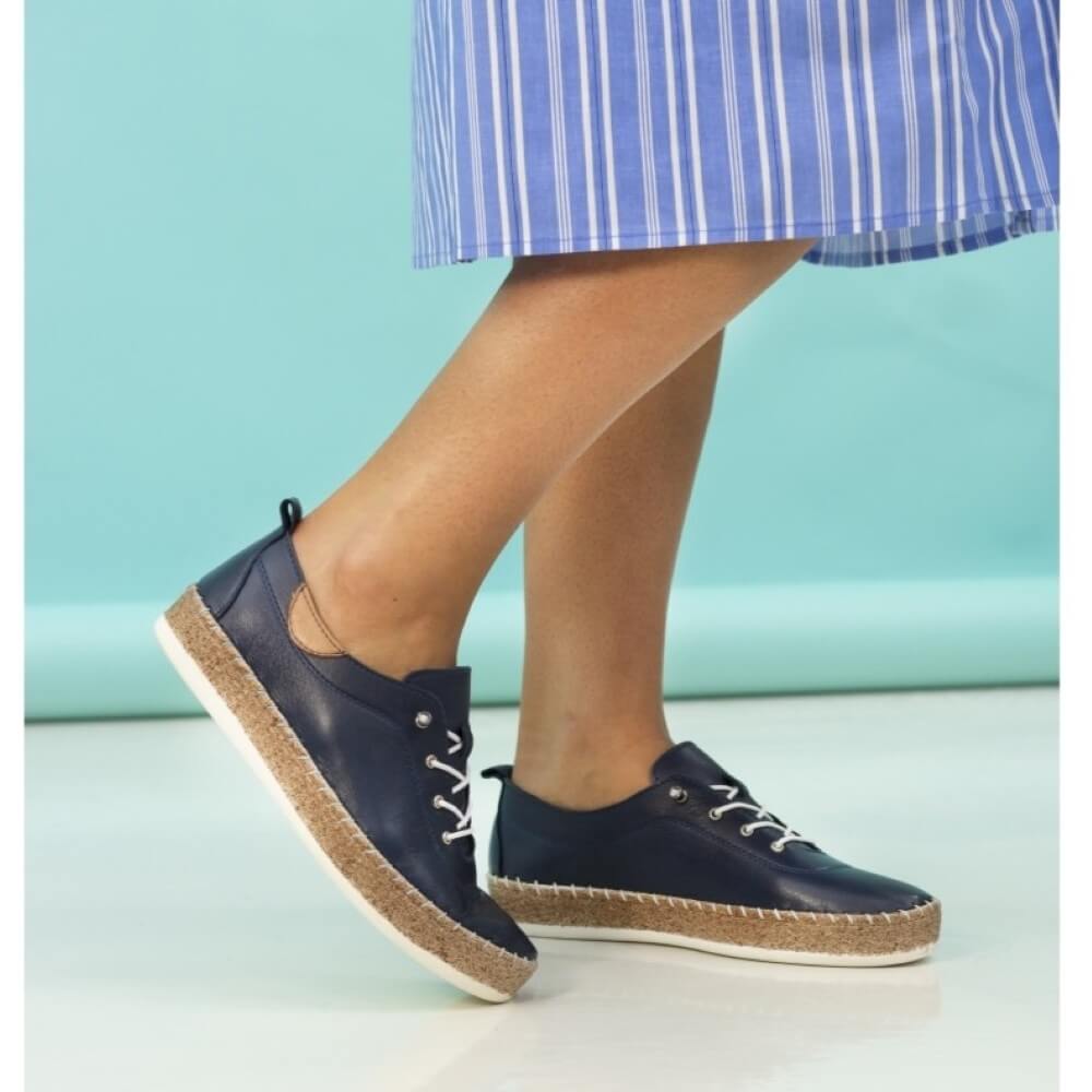Navy leather shoes with cork soles worn by a person on a light blue background