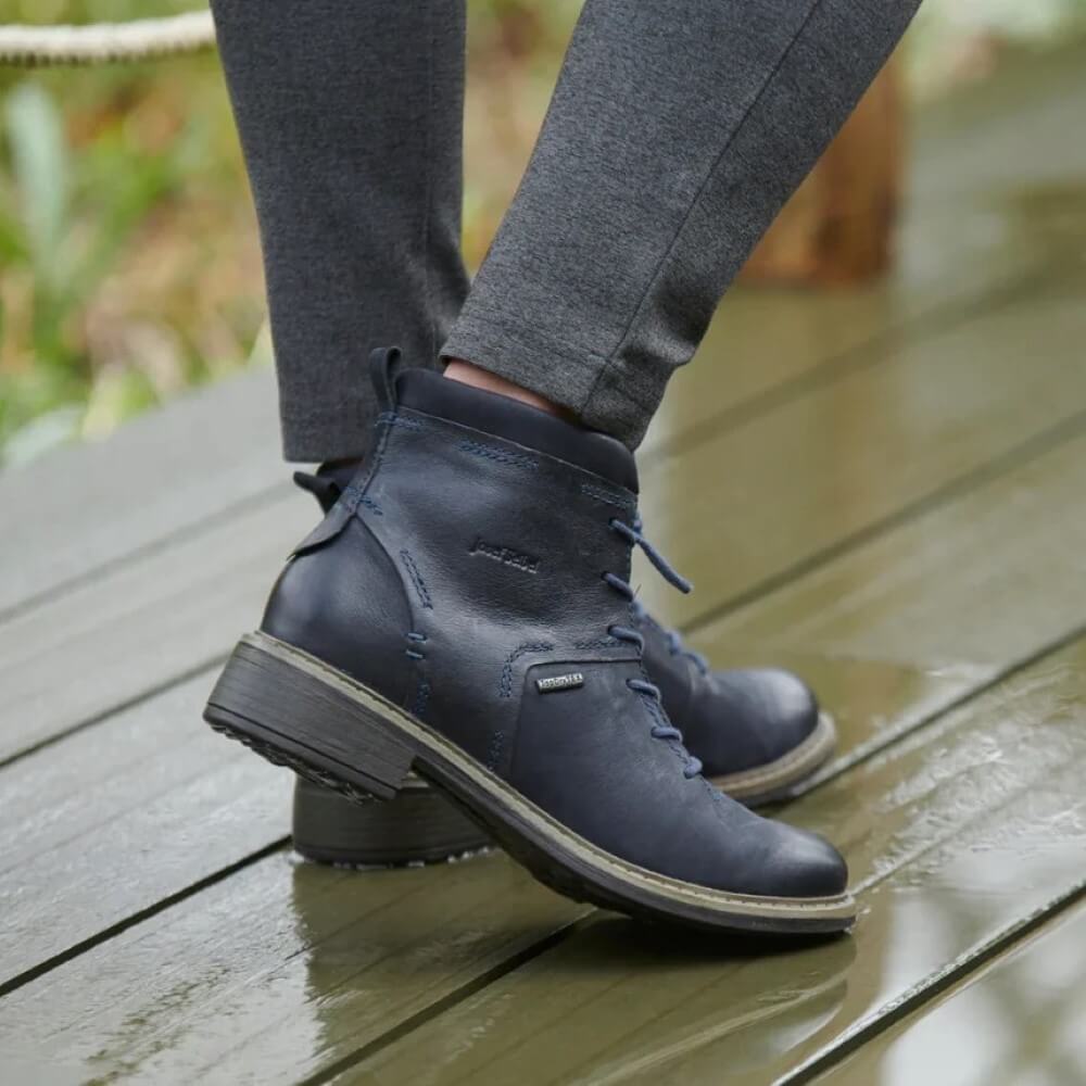 Person wearing navy blue leather waterproof boots on a wooden deck