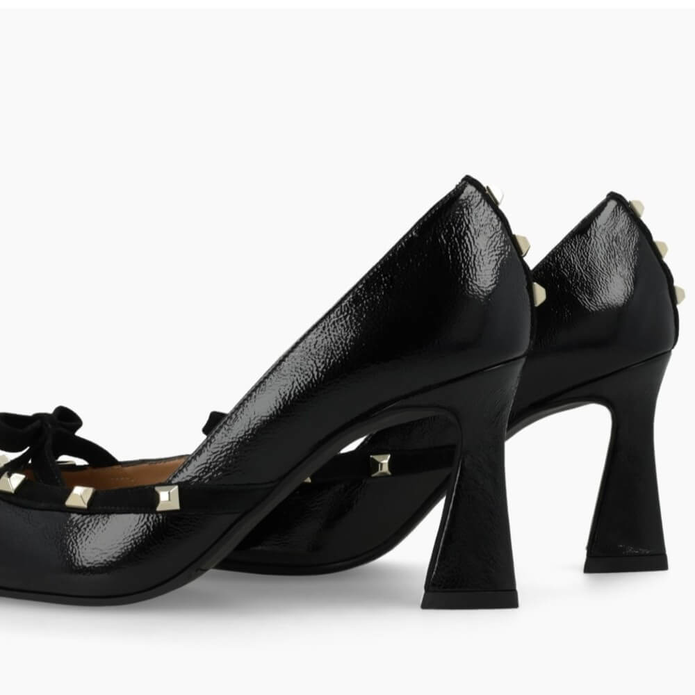 Black high-heeled shoe with decorative bow and studs on a white background Lodi RERIS pumps in black patent leather
