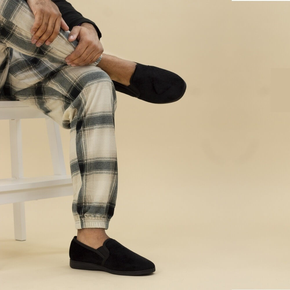 Person wearing a pair of black slippers