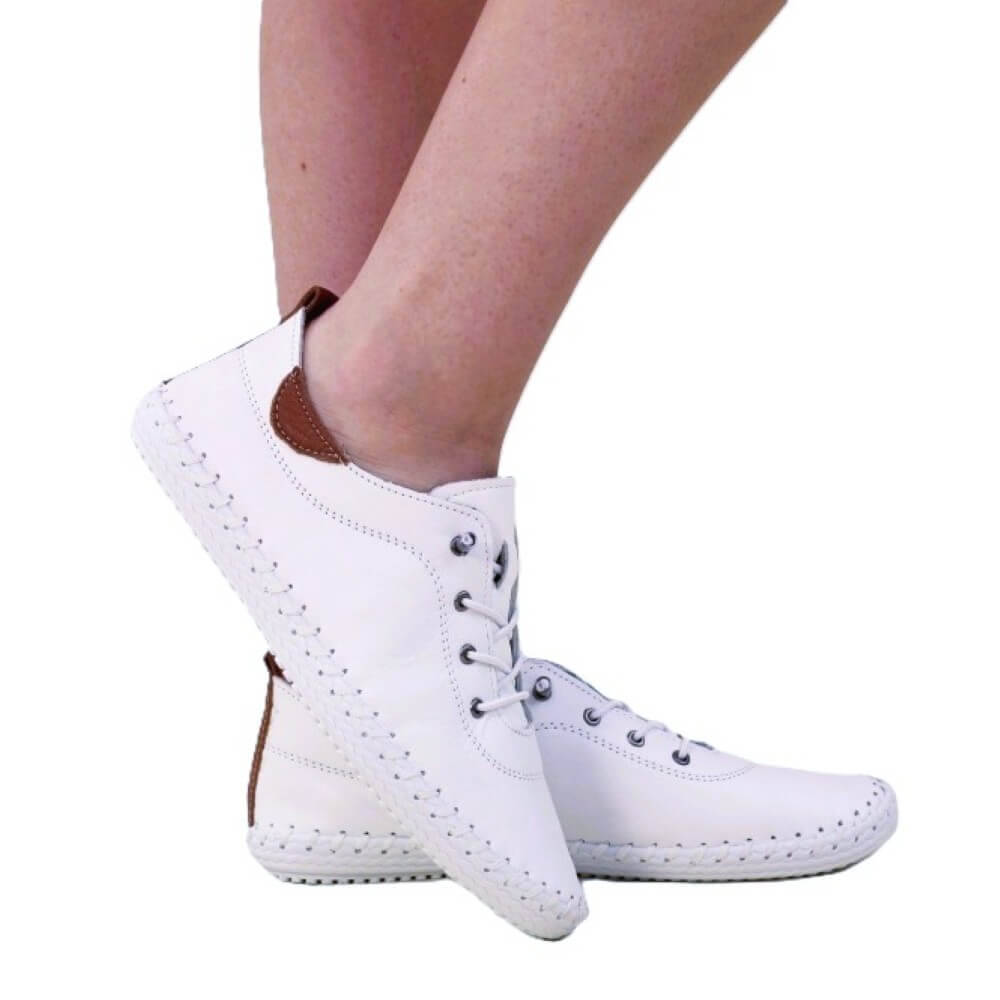 White sneakers with brown accents worn by a person on a white background