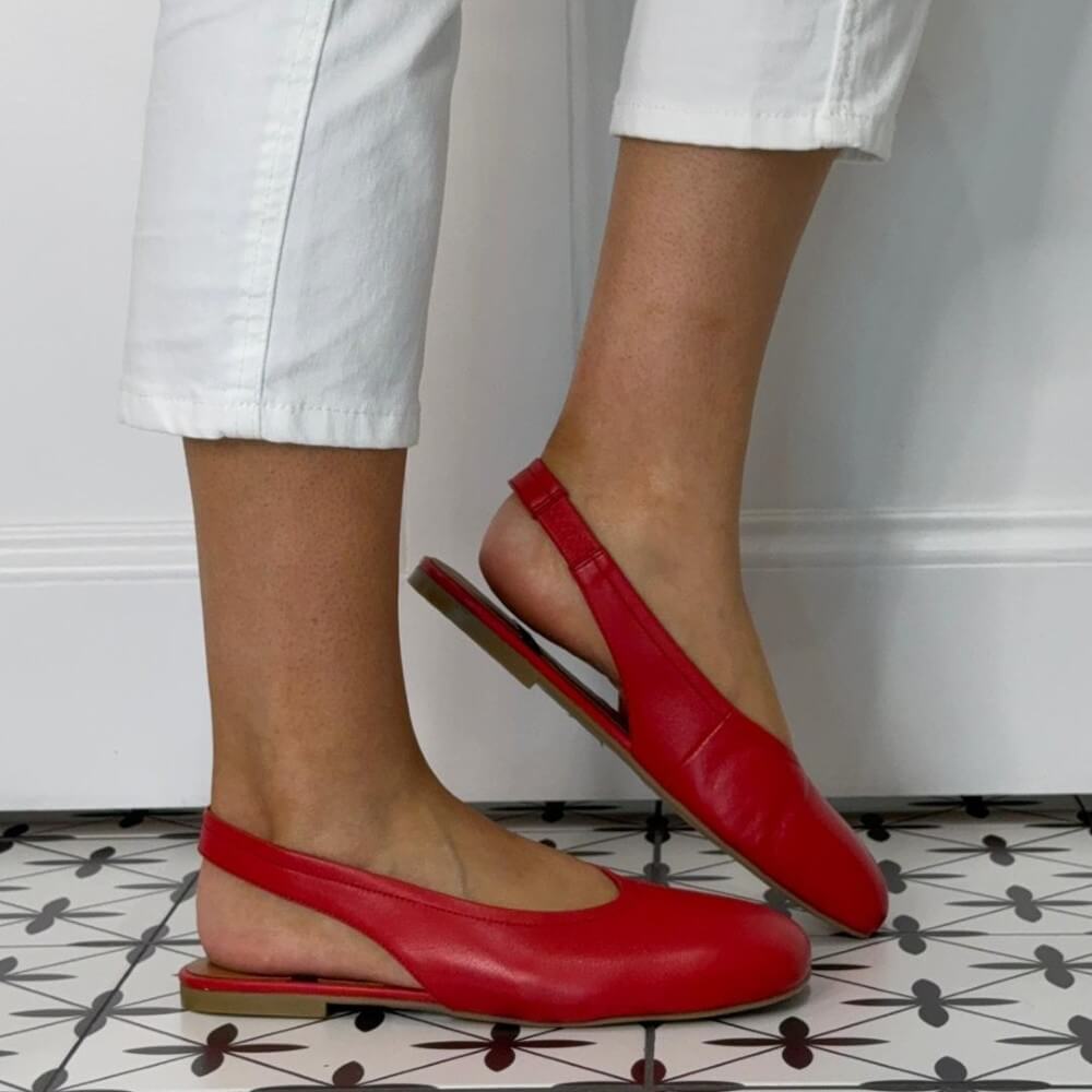 Angel Alarcon Red slingback flats worn with white pants on a patterned floor.