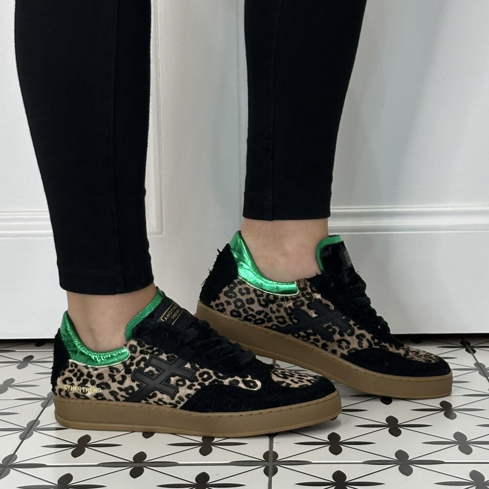 Another Trend sneakers in Black, Leopard Print and green worn with black jeans on a tiled floor