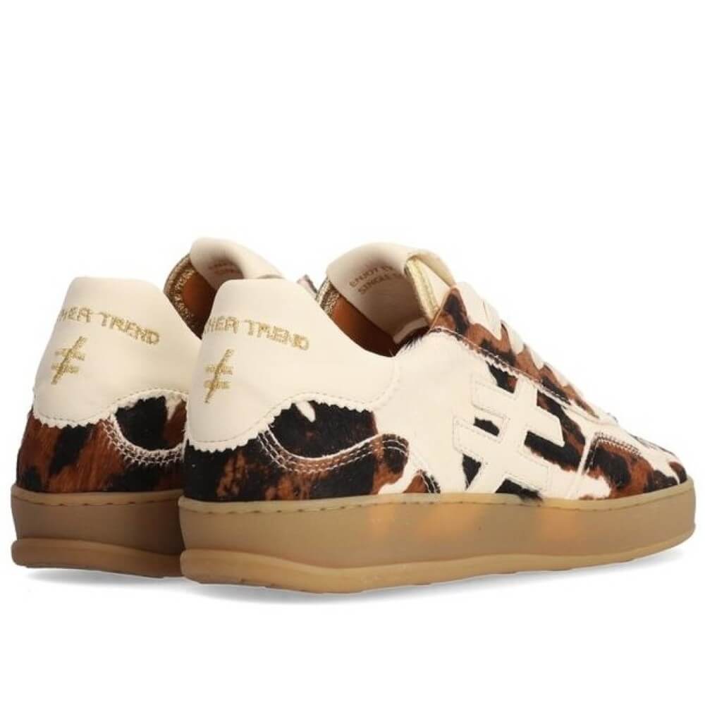 Pair of cow print sneakers with white accents on a white background