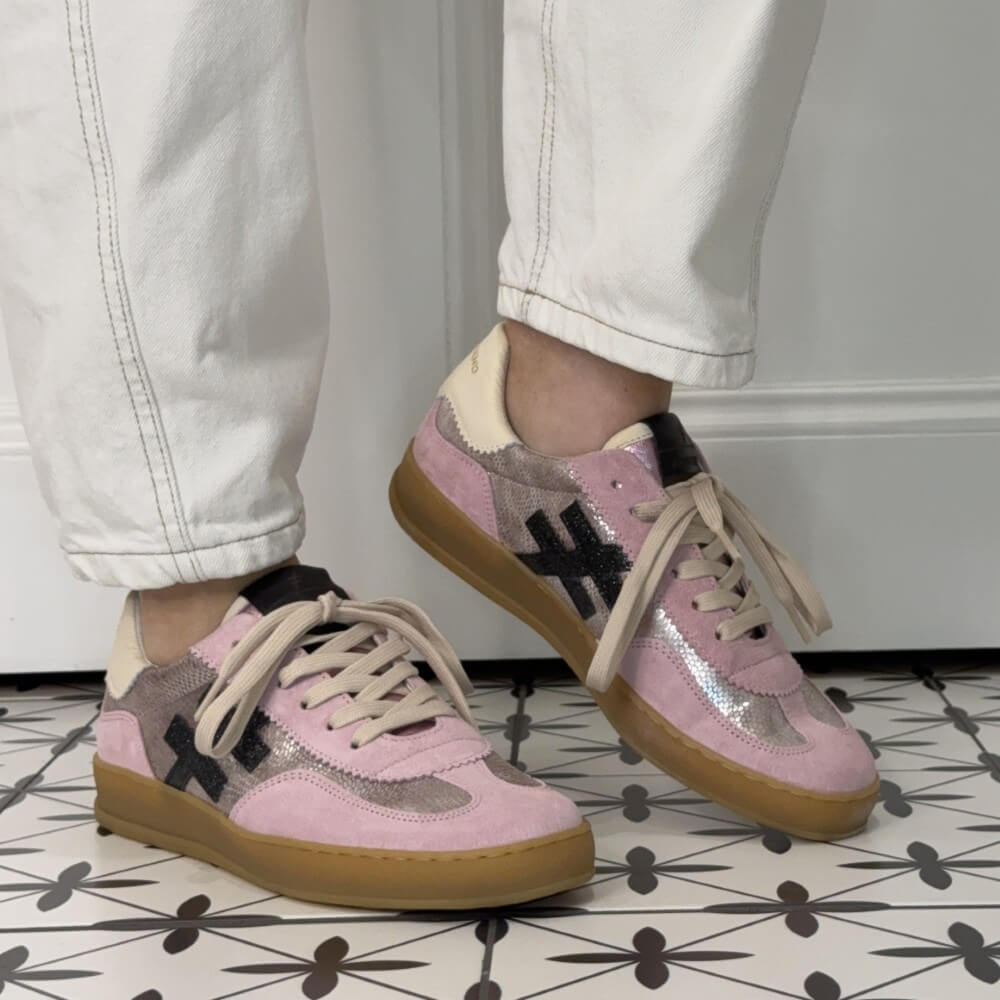 Pink and beige sneakers with a gum sole worn indoors on a tiled floor.